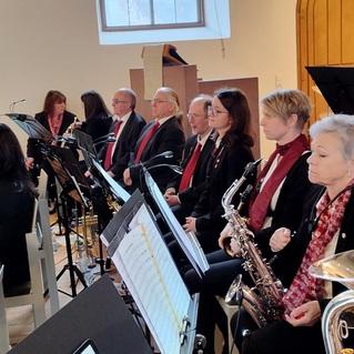 Musikgruppe in eleganter Kleidung mit Instrumenten, die in einem hellen Raum auf einer Aufführung warten.