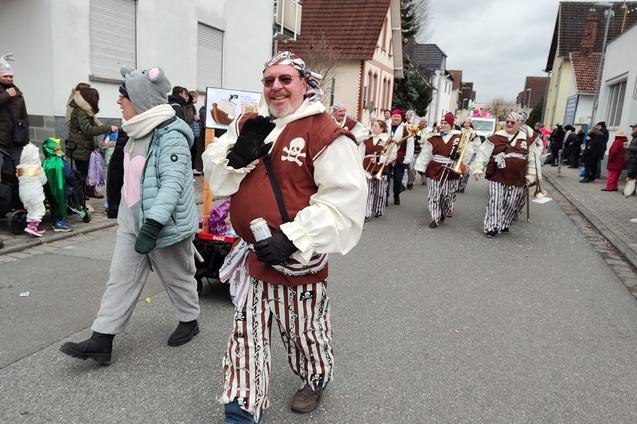Karnevalsumzug mit verkleideten Menschen, darunter ein Pirat, der fr&ouml;hlich auf der Stra&szlig;e posiert.