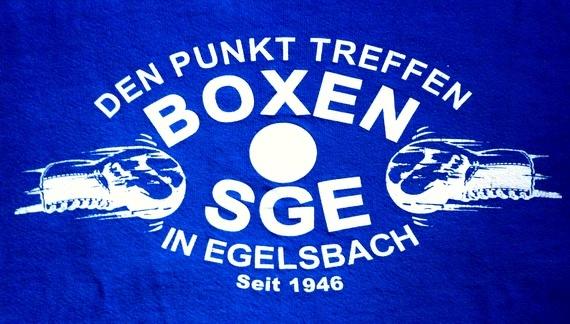 Blaues T-Shirt mit wei&szlig;em Aufdruck &bdquo;Den Punkt treffen, Boxen SGE in Egelsbach, seit 1946&ldquo; und grafischen Boxhandschuhen.