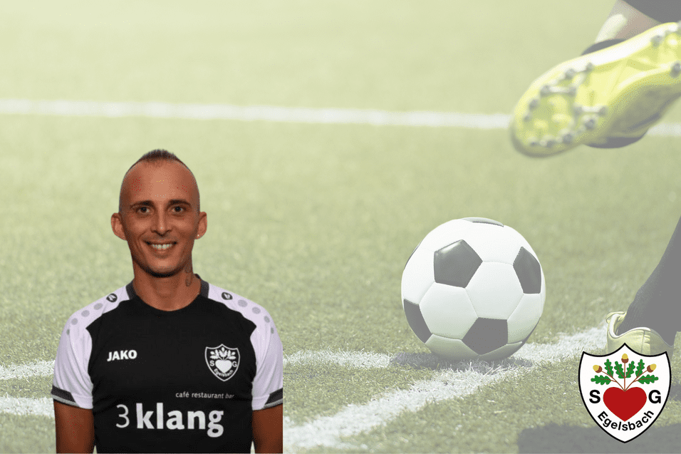 Portrait eines Fußballspielers in schwarzem Trikot mit Ball im Hintergrund auf einem Fußballfeld.