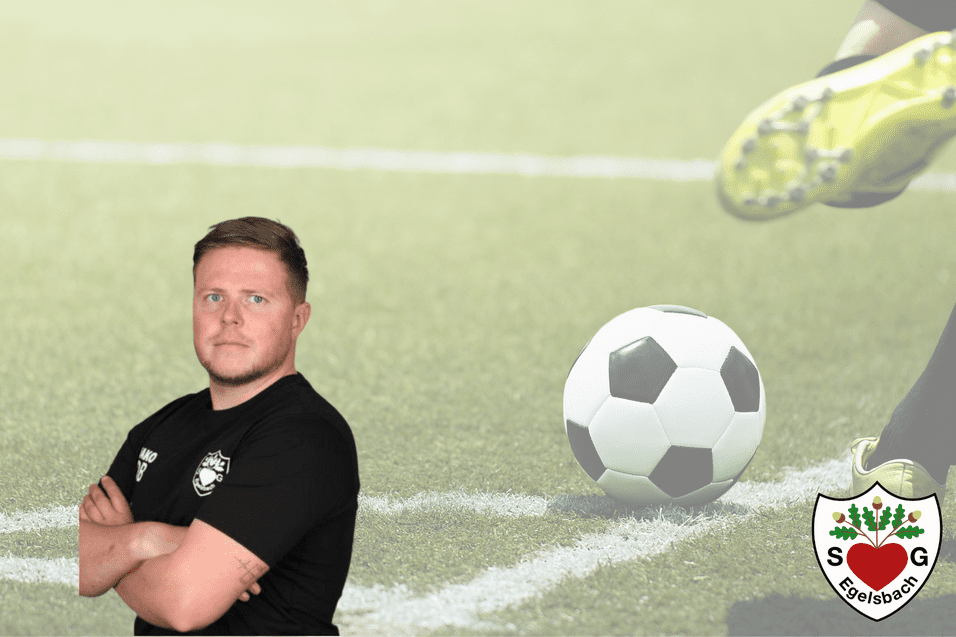 Trainer steht mit verschränkten Armen vor einem Fußballfeld, während ein Ball im Hintergrund rollt.