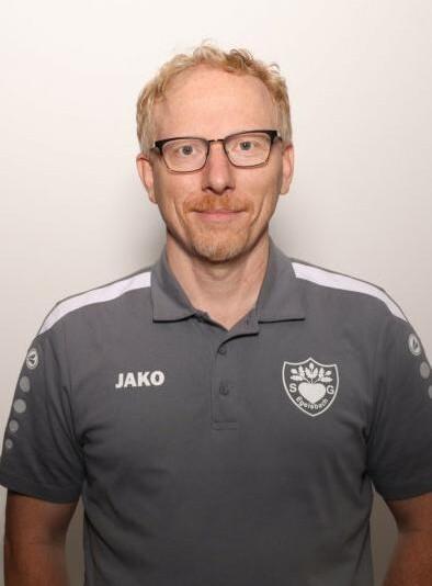 Porträt eines Mannes mit Brille, blondem Haar und grauem Polo-Shirt mit Logo und der Aufschrift "JAKO".