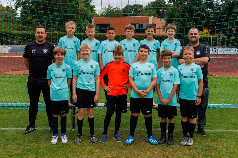 Gruppenfoto einer Jugendfu&szlig;ballmannschaft mit Spielern in t&uuml;rkisfarbenen Trikots vor einem Tor.