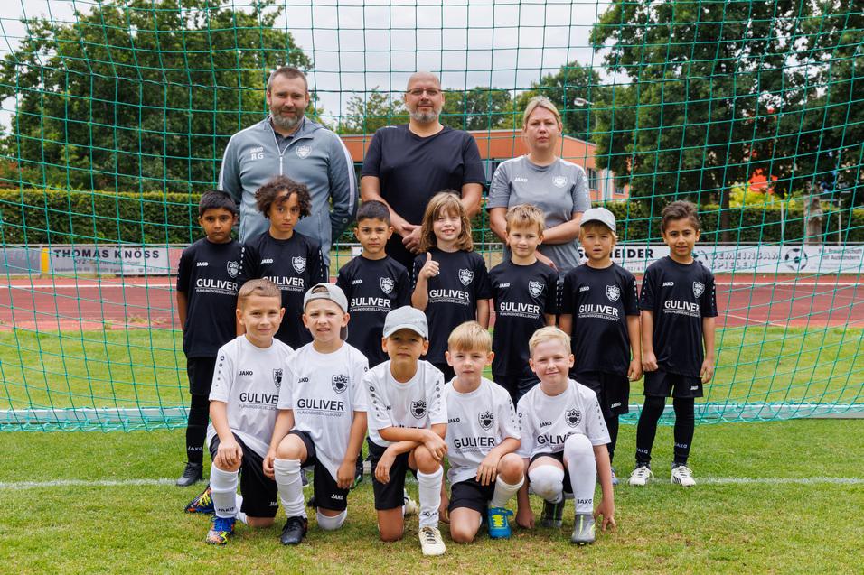 Jugendfu&szlig;ballmannschaft mit Trainern, vor einem Tor auf dem Spielfeld; Spieler in schwarzen und wei&szlig;en Trikots.
