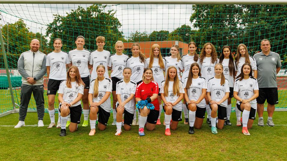 Mannschaftsfoto einer U19-Fu&szlig;ballmannschaft mit Trainer, auf einem Sportplatz vor einem Fu&szlig;balltor.
