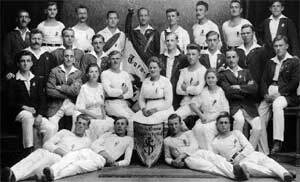Gruppe von Sportlern in historischen Uniformen, posierend mit einem Wimpel und einem Banner in Schwarz-Wei&szlig;.