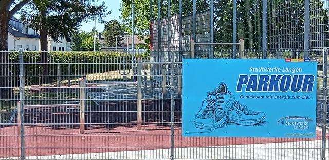 Schild mit der Aufschrift „Parkour“ und Abbildung von Sportschuhen an einem Parkour-Spielplatz.