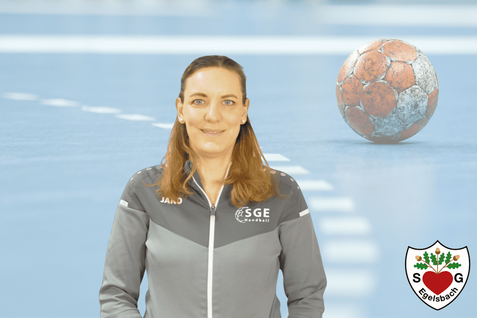 Porträt einer Frau im grauen Sportanzug, mit Handball im Hintergrund auf einem blauen Spielfeld.