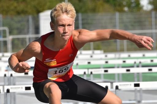 Junger L&auml;ufer &uuml;berquert eine H&uuml;rde auf einer Sportanlage w&auml;hrend eines Wettkampfs.