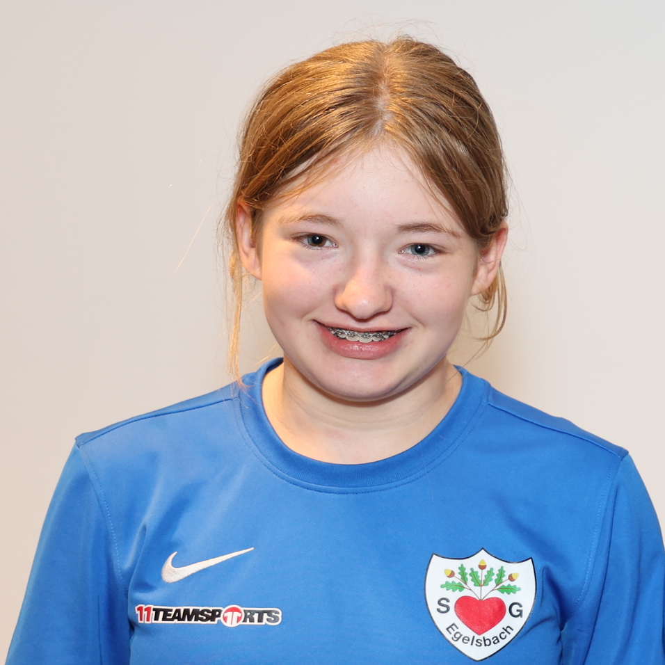 Drei Personen in blauen Sporttrikots stehen vor einem neutralen Hintergrund und l&auml;cheln in die Kamera.