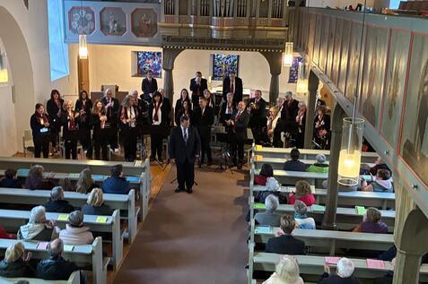 Chorauftritt in einer Kirche mit singenem Chor und Zuschauern in Kirchenb&auml;nken. Im Hintergrund eine Orgel.