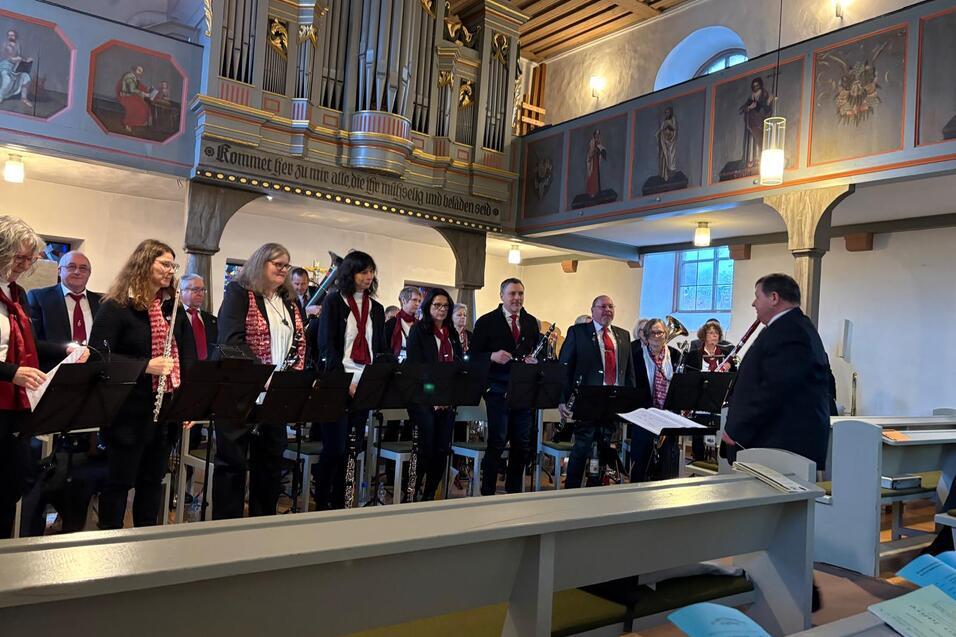 Chor bei einer Aufführung in einer Kirche, unter Leitung eines Dirigenten, mit Kirchenorgel im Hintergrund.