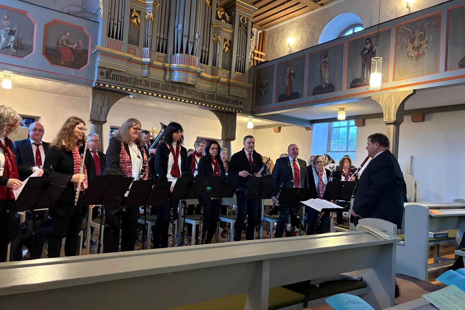 Chor bei einer Auff&uuml;hrung in einer Kirche, unter Leitung eines Dirigenten, mit Kirchenorgel im Hintergrund.