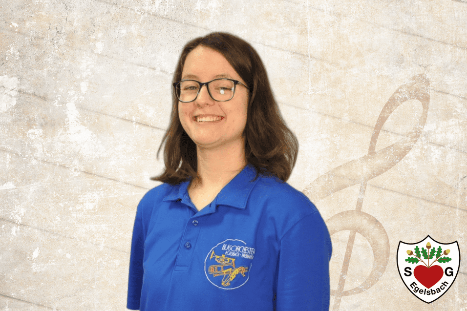 Porträt einer Person mit braunen Haaren und Brille, die ein blaues Shirt mit Logo trägt, vor einem musikalischen Hintergrund.