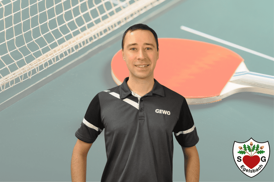 Ein junger Mann mit einem Tischtennisschläger steht vor einer Tischtennisplatte, im Hintergrund ein Netz.