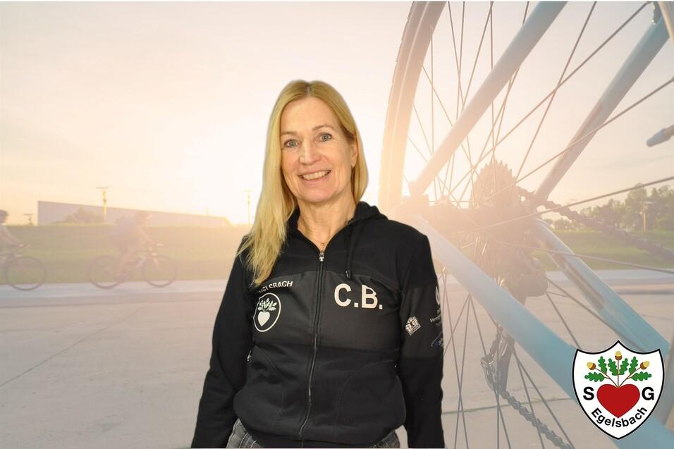 Frau in schwarzer Jacke mit Aufdruck steht vor einer Fahrrad-Silhouette und einer hellen Hintergrundleinwand.